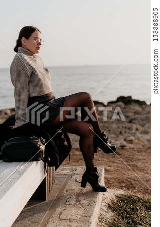 Woman Ocean Bench sitting at the seaside in autumn attire looking at the horizon during sunset copy space Woman Ocean Bench sitting at the seaside in autumn attire looking at the horizon during sunset copy space 138888905