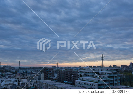 The sunrise sky visible from a residential area; the rising sun; rain clouds. The sunrise sky visible from a residential area; the rising sun; rain clouds. 138889184