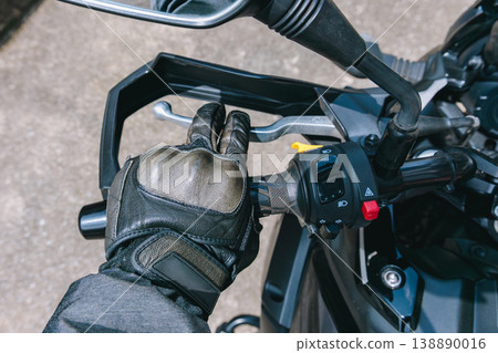 一隻手緊握著摩托車的離合器桿。 一隻手緊握著摩托車的離合器桿。 138890016