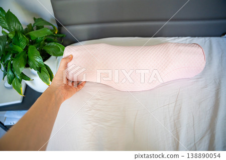 Point of view holding ergonomic orthopedic pillow over bed in bedroom. Choosing cervical support pillow for proper neck alignment, posture correction and comfortable healthy sleep at home. Point of view holding ergonomic orthopedic pillow over bed in bedroom. Choosing cervical support pillow for proper neck alignment, posture correction and comfortable healthy sleep at home. 138890054