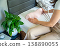 Woman holding ergonomic orthopedic pillow near bed preparing for sleep. Cervical spine support for proper neck alignment, posture correction and relief from tension, discomfort and muscle stiffness. 138890055