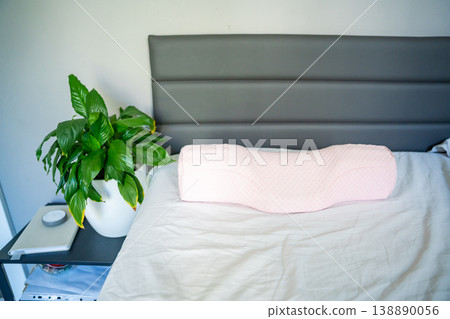 Ergonomic orthopedic pillow on bed in modern bedroom interior. Cervical support pillow for proper neck alignment, posture correction and comfortable healthy sleep at home Ergonomic orthopedic pillow on bed in modern bedroom interior. Cervical support pillow for proper neck alignment, posture correction and comfortable healthy sleep at home 138890056