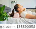 Woman positioning head on ergonomic orthopedic pillow for proper cervical spine support. Adjusting neck alignment before sleep to reduce pain, relieve tension and improve posture and sleep quality. 138890058