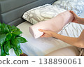 Woman holding ergonomic orthopedic pillow near bed preparing for sleep. Cervical spine support for proper neck alignment, posture correction and relief from tension, discomfort and muscle stiffness. 138890061