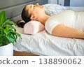 Woman lying on bed using ergonomic orthopedic pillow for cervical spine support. Proper neck alignment during sleep for posture correction, muscle relaxation, pain relief and comfortable healthy rest 138890062