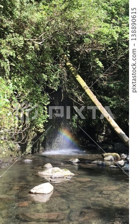 A miraculous sight: A vibrant rainbow appears over a waterfall. A mystical landscape that evokes a sense of purification and hope, woven from the lush green valley and clear stream. A miraculous sight: A vibrant rainbow appears over a waterfall. A mystical landscape that evokes a sense of purification and hope, woven from the lush green valley and clear stream. 138890615