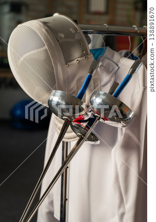 Fencing uniforms and masks hang on hangers. No people. Fencing uniforms and masks hang on hangers. No people. 138891670