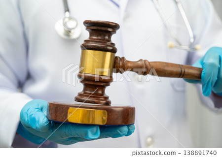 Doctor holding judge gavel, forensic medicine, medical law and crime justice. Doctor holding judge gavel, forensic medicine, medical law and crime justice. 138891740