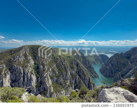 Mountain river in a canyon against a background of green forest and blue sky 138891973