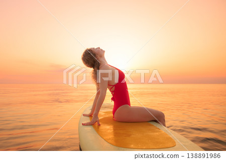 Young woman walking on sup board by the sea during summer vacation Young woman walking on sup board by the sea during summer vacation 138891986