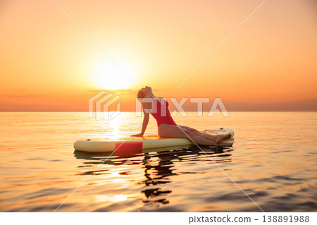 Young woman walking on sup board by the sea during summer vacation Young woman walking on sup board by the sea during summer vacation 138891988