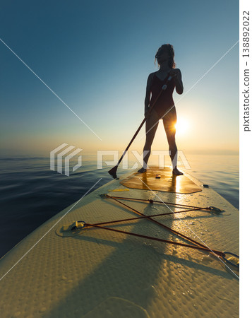 Young woman walking on sup board by the sea during summer vacation Young woman walking on sup board by the sea during summer vacation 138892022