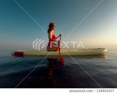 Young woman walking on sup board by the sea during summer vacation Young woman walking on sup board by the sea during summer vacation 138892027