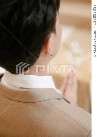 Rear View of Man in Tan Suit Wearing Silver Hoop Earring with Hands in Prayer Pose Rear View of Man in Tan Suit Wearing Silver Hoop Earring with Hands in Prayer Pose 138892055