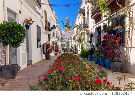 A bright white street lined with colorful flower pots and blooming plants creates a charming Mediterranean scene in Estepona, Spain A bright white street lined with colorful flower pots and blooming plants creates a charming Mediterranean scene in Estepona, Spain 138892434