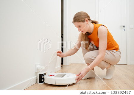 A woman holding a robot vacuum cleaner A woman holding a robot vacuum cleaner 138892497