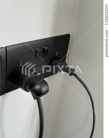 Electrical outlet with two black plugs on a white wall providing power connection background 138892850