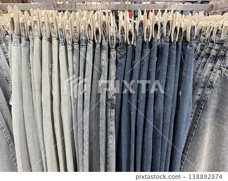 Jeans hanging on rack in store creating a denim texture background with varied shades of blue Jeans hanging on rack in store creating a denim texture background with varied shades of blue 138892874