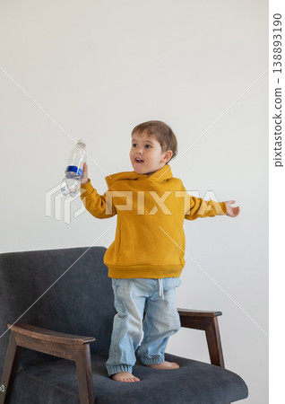 A funny two-year-old boy plays with a bottle of water. A funny two-year-old boy plays with a bottle of water. 138893190