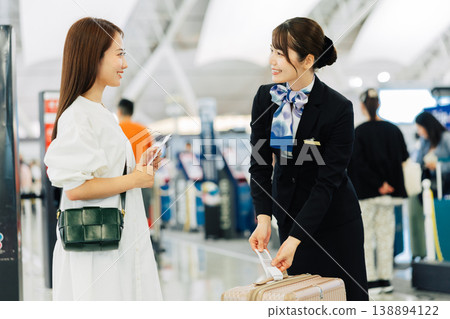 A female airport ground staff member attaches a tag to a traveler's carry-on bag. (Photo courtesy of Kansai International Airport (KIX)) A female airport ground staff member attaches a tag to a traveler's carry-on bag. (Photo courtesy of Kansai International Airport (KIX)) 138894122