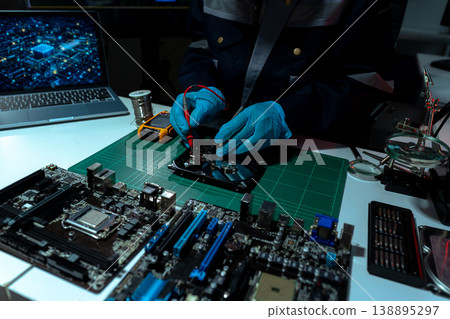Computer Hardware Technician Repairing Motherboard with Soldering Iron in Electronics Lab. 138895297