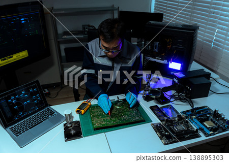 Computer Hardware Technician Repairing Motherboard with Soldering Iron in Electronics Lab. 138895303