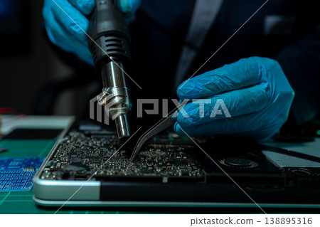 Computer Hardware Technician Repairing Motherboard with Soldering Iron in Electronics Lab. Computer Hardware Technician Repairing Motherboard with Soldering Iron in Electronics Lab. 138895316