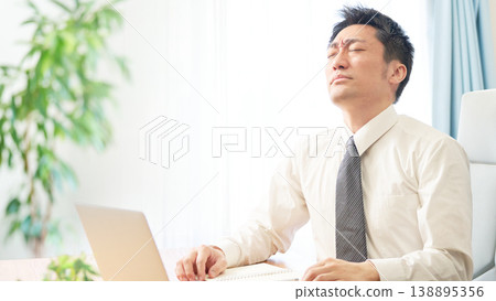 一名男上班族閉上眼睛,臉上露出痛苦的表情,顯然被繁重的案頭工作壓得喘不過氣來。 一名男上班族閉上眼睛,臉上露出痛苦的表情,顯然被繁重的案頭工作壓得喘不過氣來。 138895356