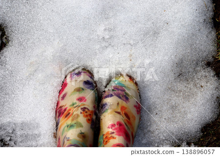Toes of colored rubber boots on melting snow 138896057
