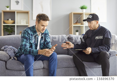 Portrait of a police man officer talking to witnesses or interrogating a young worried man. Portrait of a police man officer talking to witnesses or interrogating a young worried man. 138896370
