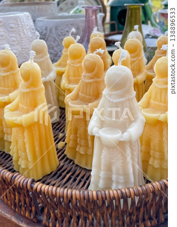 Beautiful handmade beeswax candles in traditional female shapes displayed in a rustic wicker basket 138896533