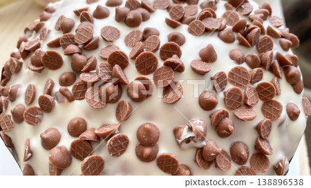 Delicious Easter cake with white sugar glaze and many milk chocolate chips close up macro shot Delicious Easter cake with white sugar glaze and many milk chocolate chips close up macro shot 138896538