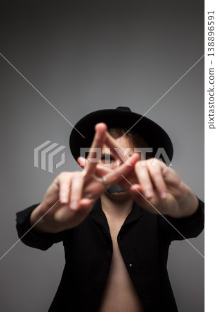 Conceptual portrait of a woman in a black hat with tape on her mouth showing a stop sign with her hands. Silence, censorship, freedom of speech, and domestic violence concept 138896591