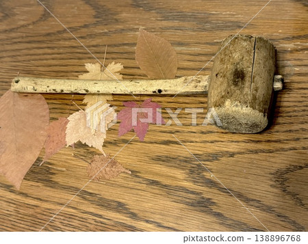 A wooden mallet, acorns, and fallen leaves on an old wooden table. A wooden mallet, acorns, and fallen leaves on an old wooden table. 138896768