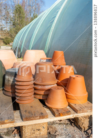 Clay terracotta pots arranged near a greenhouse. Clay terracotta pots arranged near a greenhouse. 138896817
