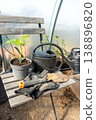 Garden tools and a seedling in a pot standing on a wooden chair.  138896820