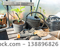 Garden tools and a seedling in a pot standing on a wooden chair.  138896826