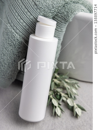 White flip top cosmetic bottle mockup near leaves and sage green bath towel. Unbranded packaging 138897714