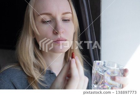Woman taking iron supplement capsule with glass of water. Female health care, iron deficiency anemia treatment, vitamins and minerals intake for wellness. Woman taking iron supplement capsule with glass of water. Female health care, iron deficiency anemia treatment, vitamins and minerals intake for wellness. 138897773