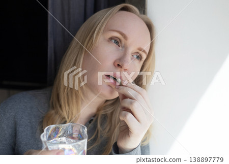 Woman taking iron supplement capsule with glass of water. Female health care, iron deficiency anemia treatment, vitamins and minerals intake for wellness. 138897779