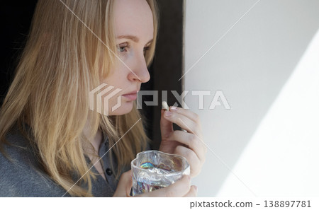 Woman taking iron supplement capsule with glass of water. Female health care, iron deficiency anemia treatment, vitamins and minerals intake for wellness. Woman taking iron supplement capsule with glass of water. Female health care, iron deficiency anemia treatment, vitamins and minerals intake for wellness. 138897781