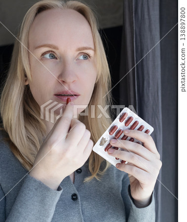 Woman taking iron supplement capsule with glass of water. Female health care, iron deficiency anemia treatment, vitamins and minerals intake for wellness. Woman taking iron supplement capsule with glass of water. Female health care, iron deficiency anemia treatment, vitamins and minerals intake for wellness. 138897800