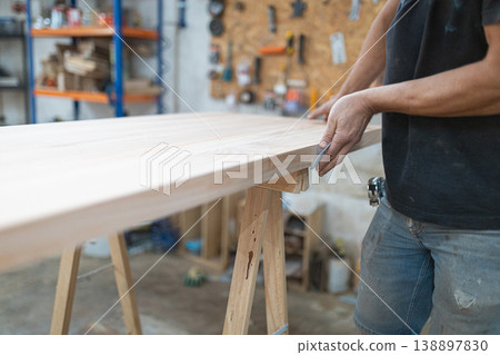 Carpenter sanding wood surface creating furniture in workshop Carpenter sanding wood surface creating furniture in workshop 138897830