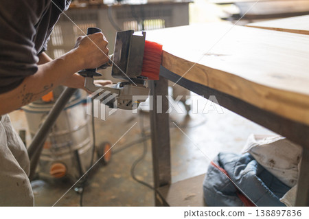 Woodworker sanding natural edge wooden slab in workshop Woodworker sanding natural edge wooden slab in workshop 138897836