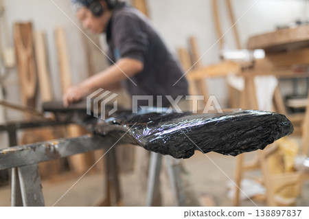 Artisan applying finish coating to live edge wood slab 138897837
