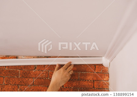 Installing crown molding in room corner, interior renovation and finishing work 138899154
