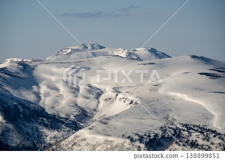 The summit of Mount Tomuraushi in winter, Hokkaido. A breathtaking view that represents the magnificent nature of Hokkaido. The snow-covered summit and the clear blue sky create a stunning winter scene. The summit of Mount Tomuraushi in winter, Hokkaido. A breathtaking view that represents the magnificent nature of Hokkaido. The snow-covered summit and the clear blue sky create a stunning winter scene. 138899851