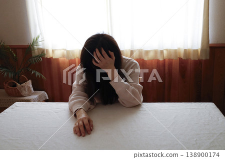 A woman, with her hair unkempt and still in her loungewear, hangs her head listlessly. A woman, with her hair unkempt and still in her loungewear, hangs her head listlessly. 138900174