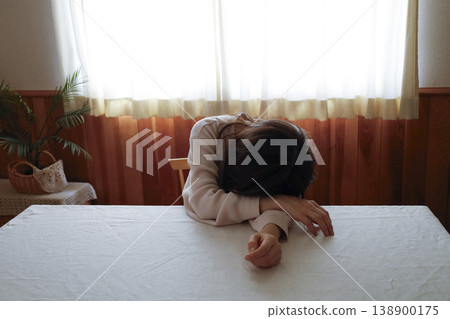 A woman with her hair unkempt and still in her loungewear, her face downcast. 138900175