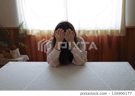 一位頭髮蓬亂、身穿家居服的女子無精打采地低著頭。 138900177